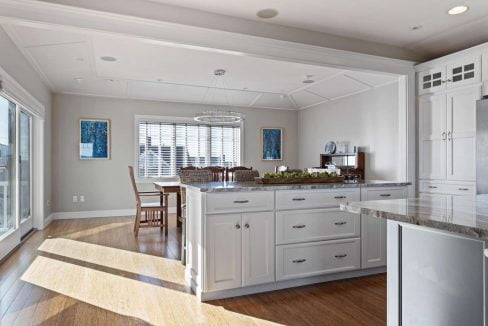 A bright, modern kitchen with white cabinetry, stainless steel appliances, hardwood floors, and a central island.