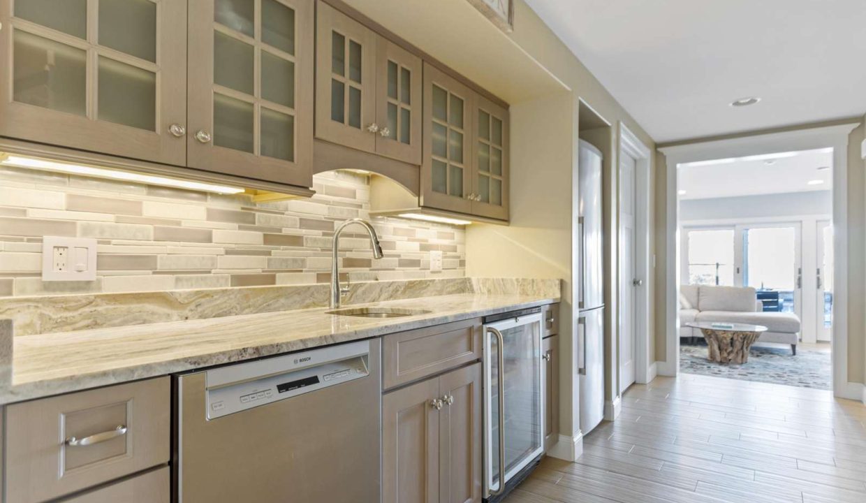 Modern kitchen interior with stainless steel appliances, marble countertops, and under-cabinet lighting.