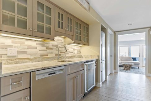 Modern kitchen interior with stainless steel appliances, marble countertops, and under-cabinet lighting.