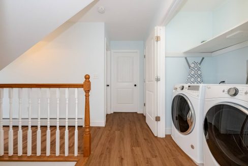 An interior view of a laundry room with modern appliances next to a staircase.
