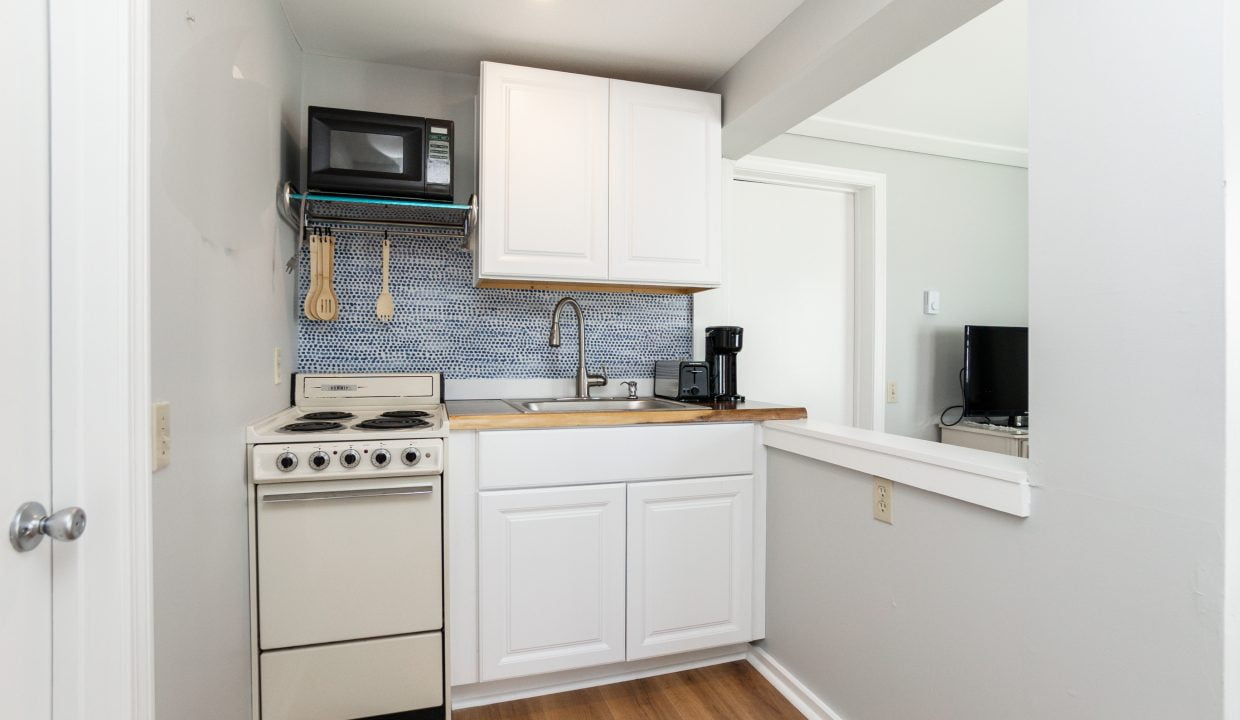 A compact, modern kitchen with white cabinetry and stainless steel appliances.