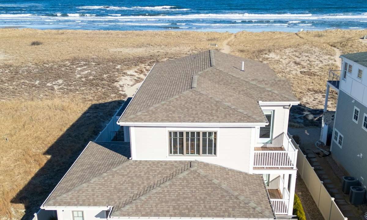 Aerial view of a large coastal home with a beachfront location.