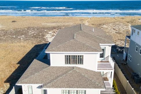 Aerial view of a large coastal home with a beachfront location.