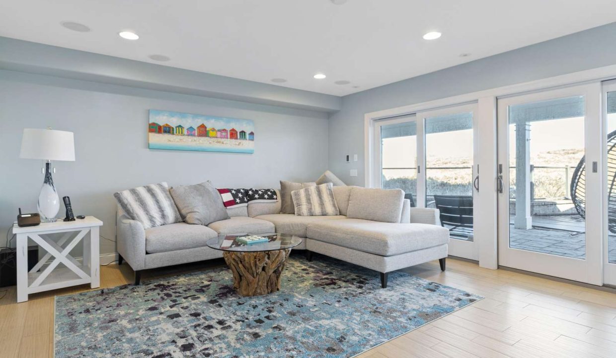 Modern living room with l-shaped sofa, area rug, and sliding doors leading to an outdoor space.