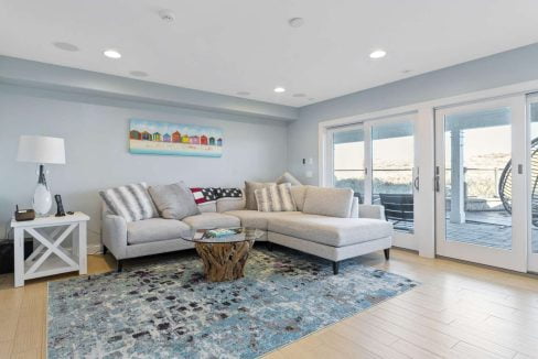 Modern living room with l-shaped sofa, area rug, and sliding doors leading to an outdoor space.