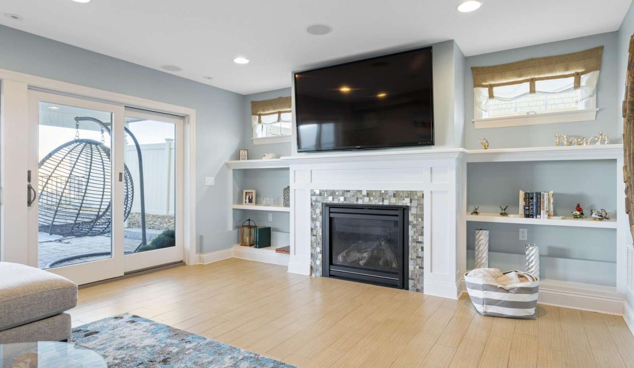 A modern living room with a fireplace, mounted television, and sliding door leading to an outdoor area.