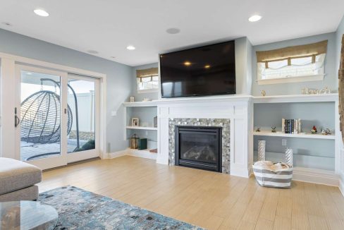 A modern living room with a fireplace, mounted television, and sliding door leading to an outdoor area.