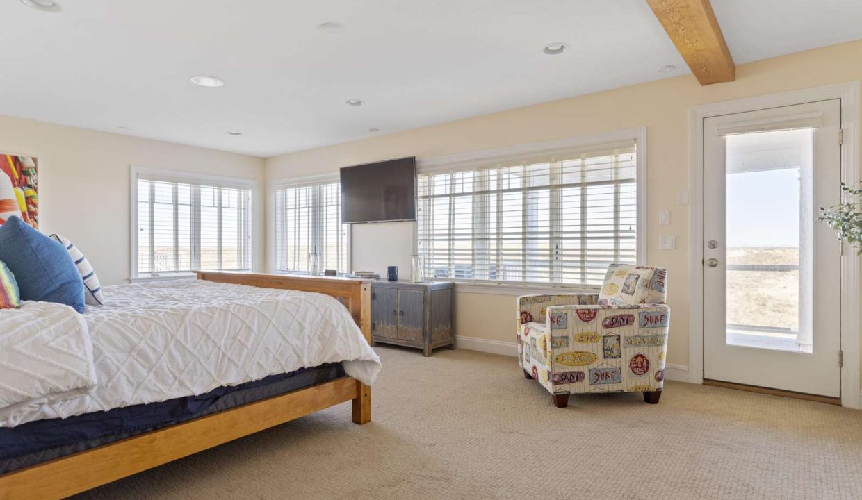 Spacious, well-lit bedroom with a large bed, multiple windows, and a door leading outside.