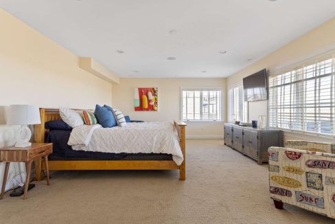 A spacious, well-lit bedroom with a king-sized bed, bright artwork, and a seating area by the window.