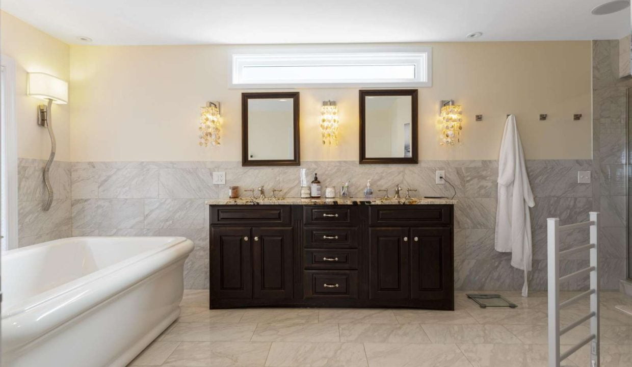 Modern bathroom interior with a double vanity, wall-mounted mirrors, and a freestanding bathtub.