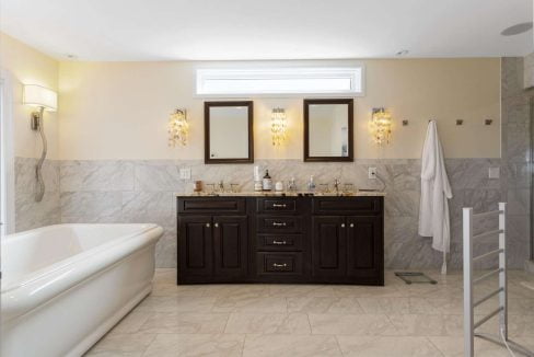 Modern bathroom interior with a double vanity, wall-mounted mirrors, and a freestanding bathtub.