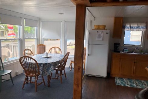 A cozy dining area with a wooden table and chairs adjacent to a kitchen with wooden cabinetry and a white refrigerator.