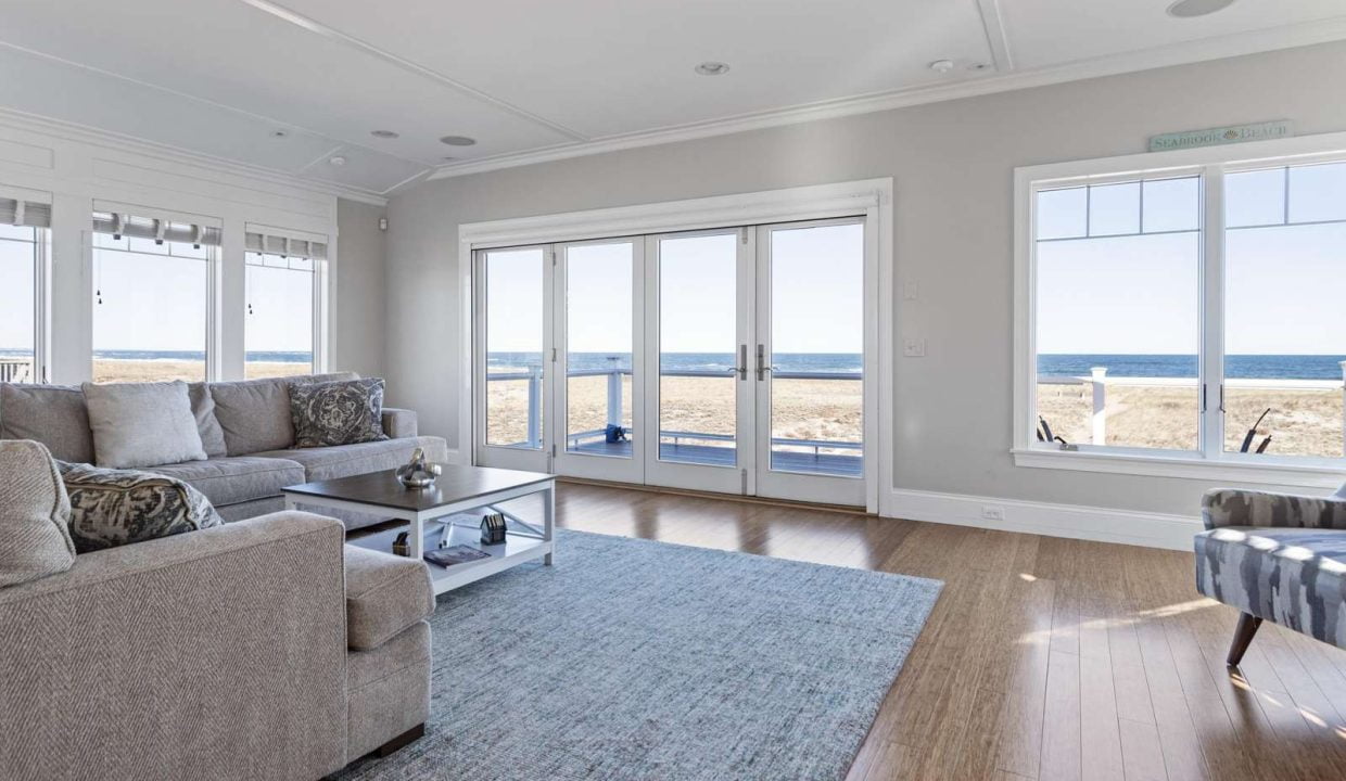 A bright, contemporary living room with sliding glass doors that open to a beach view.