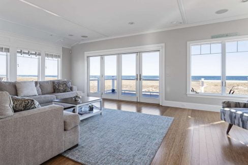 A bright, contemporary living room with sliding glass doors that open to a beach view.