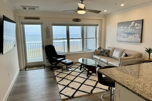 A modern living room with a leather sofa and chair overlooking an ocean view through balcony doors.