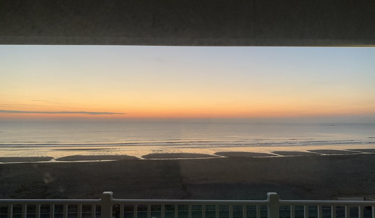 Sunset view over a beach from a balcony.