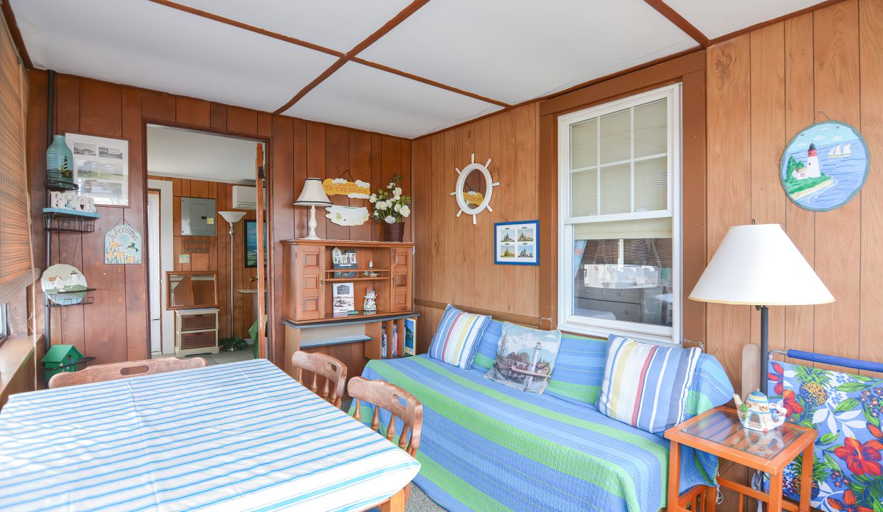 A cozy, nautical-themed living room with wood paneling, striped sofa, and maritime decorations.