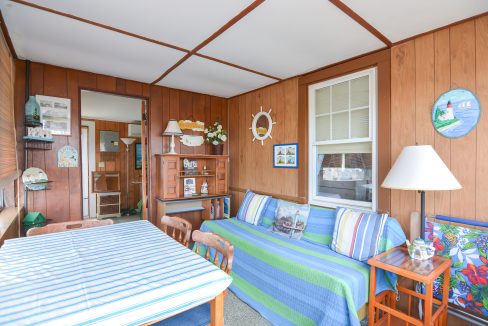 A cozy, nautical-themed living room with wood paneling, striped sofa, and maritime decorations.