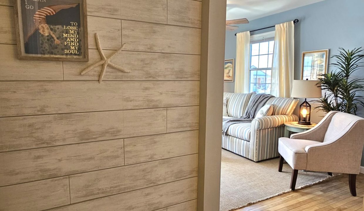 Coastal-themed living area with a striped sofa, armchair, and nautical wall decor.