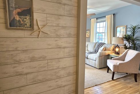 Coastal-themed living area with a striped sofa, armchair, and nautical wall decor.